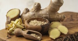 Ingwerwurzel und Ingwerpulver in einer Holzschale