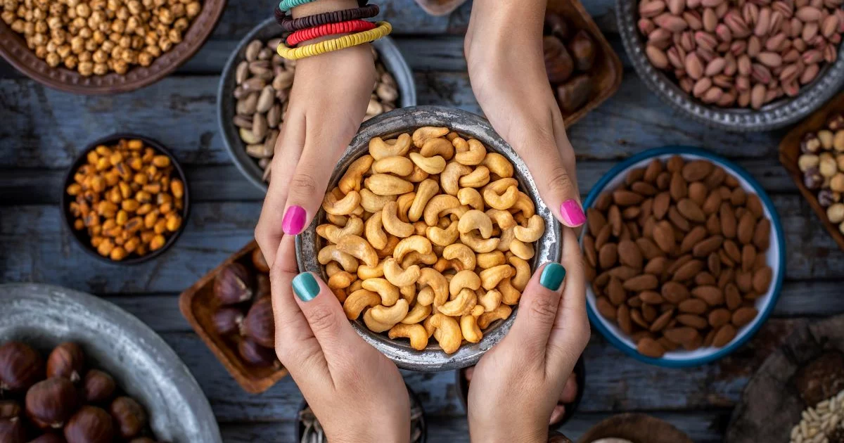 Zwei Personen halten eine Schale mit Cashewnüssen.