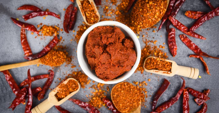 Cayennepfeffer in einer Schale, umgeben von Paprika und Kernen