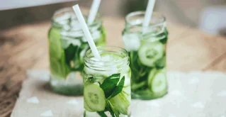 Gurkenwasser mit Minzeblättchen im Glas mit Strohhalm.