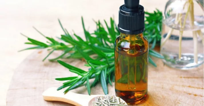 Glasfläschchen mit Rosmarinöl und Zweig