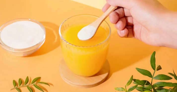 Natriumascorbat in Pulver Form und ein Glas mit Saft