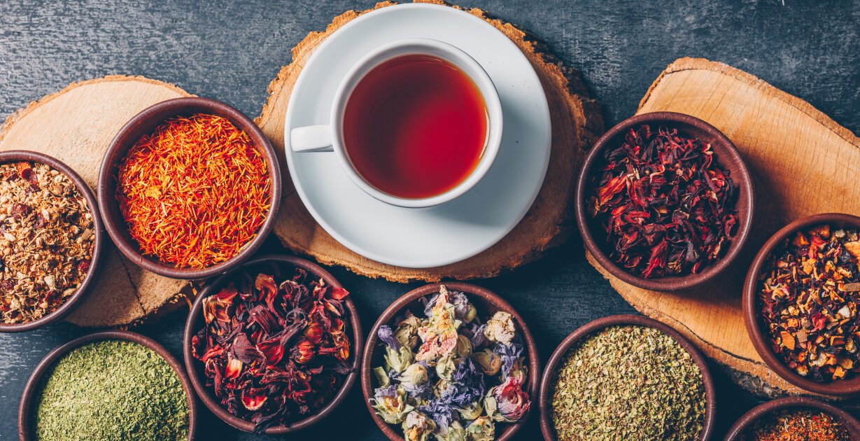 eine Tasse Tee mit trockenen Gewürzen in kleinen Schälchen daneben