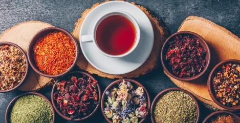 eine Tasse Tee mit trockenen Gewürzen in kleinen Schälchen daneben