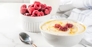 Grießbrei mit Milch mit einer Schüssel Himbeeren