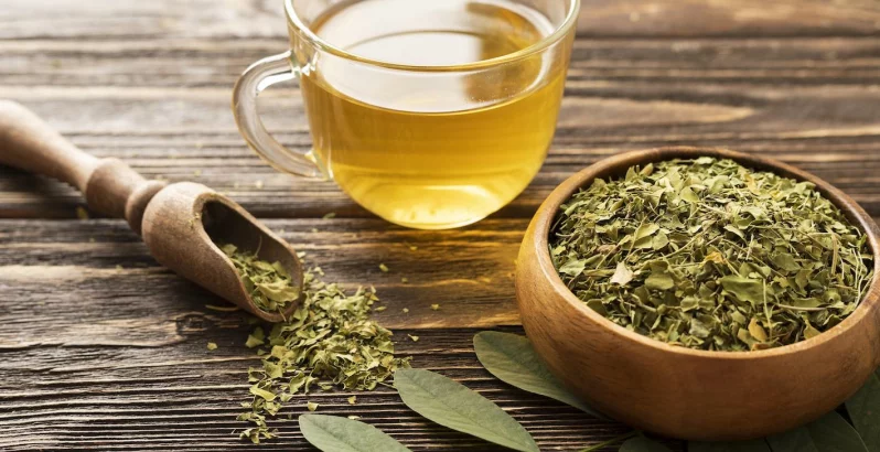 Tee mit einer Schale trockenen Tees daneben