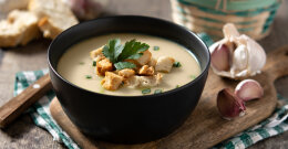 Suppe in einer schwarzen Schüssel mit Gemüse.