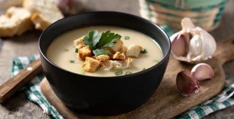 Suppe in einer schwarzen Schüssel mit Gemüse.
